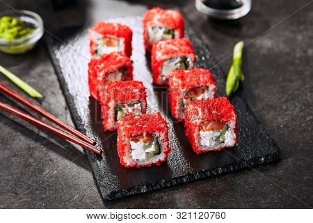 Alaska salmon uramaki sushi restaurant menu with rice, cream cheese, salmon, cucumber, flying fish caviar and nori close up. Macro shot of japanese food uramaki rolls with red tobiko closeup