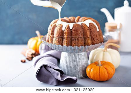 Pumpkin Bundt Cake On A Cake Stand With Cream Cheese Filling And Glaze Pouring Over