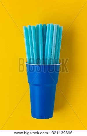 Dark Blue Plastic Single Use Cup On Yellow Background. Many Drinking Straws Inside The Cup. Concept 