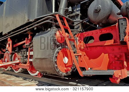 Fragment Of An Old Steam Locomotive On Rails, Wheels And Pistons, Cylinders And Powertrain