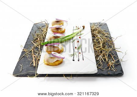 Herring Canape with Potato and Onion on Natural Rustic Background. Beautiful Creative Sea Food Design of Fish Fillet with Scallions on Dry Hay and Black Slate