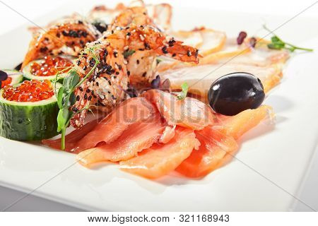 Fish platter with pink salmon, grilled eel, oil fish balyk and red caviar on elegant restaurant plate isolated on white background. Exquisite serving thin slices of salted and dried delicious seafood