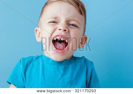 Ill Young Child With A Thermomether, Measuring The Height Of His Fever And Looking Into The Camera