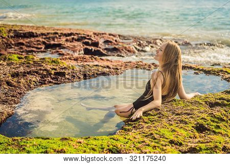 Young Woman Tourist On Pantai Tegal Wangi Beach Sitting In A Bath Of Sea Water, Bali Island, Indones