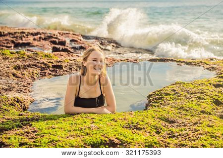 Young Woman Tourist On Pantai Tegal Wangi Beach Sitting In A Bath Of Sea Water, Bali Island, Indones