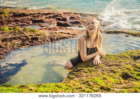 Young Woman Tourist On Pantai Tegal Wangi Beach Sitting In A Bath Of Sea Water, Bali Island, Indones