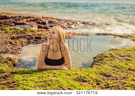 Young Woman Tourist On Pantai Tegal Wangi Beach Sitting In A Bath Of Sea Water, Bali Island, Indones