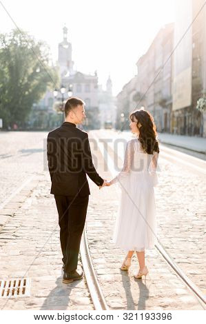 Happy Young Chinese Couple Walking On The Streets Of Old City Center, Standing On The Tramline. Anci