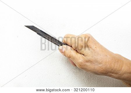 Senior Woman's Hand Holding A Cutter Knife On White Background