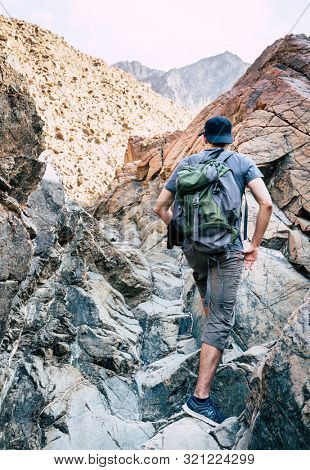 A man is hiking through a wadi in Hajar Mountains near Hatta, UAE