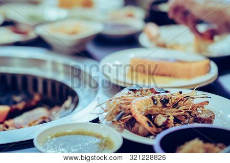 People Grilling Meat On A Smokeless Barbecue Grill In A Restaurant. Selective Focus On Shrimps.