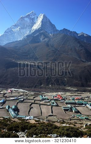 Sagarmatha national park, Dingboche, Nepal - May 20, 2019: View of Dingboche village (4410 m) and Ama Dablam mountain (6856 m) from the trail of Everest trek