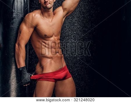 Sexy Handsome Man With Beautiful Muscular Body And Mini Red Pants Is Posing On The Dark Background N