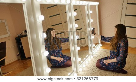 The Girl Sits On The Floor And Makes Selfies At The Makeup Mirrors At Home.