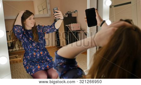The Girl Sits On The Floor And Makes Selfies At The Makeup Mirrors At Home.