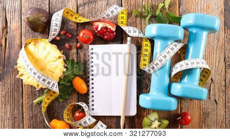 diet food concept with dumbbell, fruit and notbook