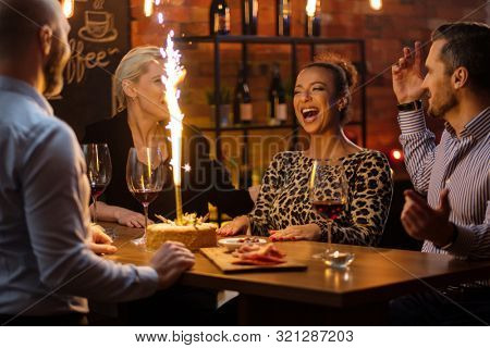 Group of friends celebrating birthday in a cafe behind bar counter