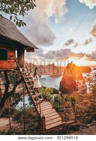 Travel Woman Looking Sunrise View Tree House With Daimond  Beach, Nusa Penida Island Bali ,indonesia