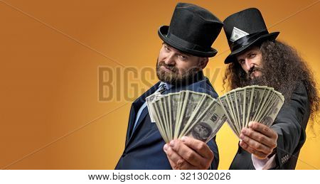 Two gentelmen holding dolars in their hands