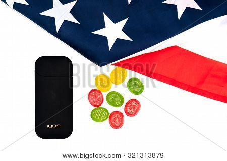 Black Iqos Box, Americas Flag And Multicolored Sweet Candy Lollipops On White Background. Iqos Elect