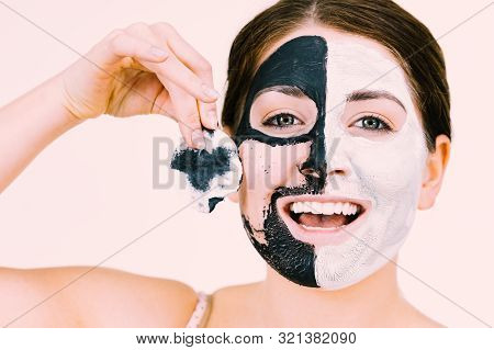 Woman With Clay Carbo Black Mask On One Half Face And White Mud On Second Half. Girl Removing Cosmet