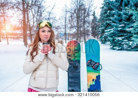 Girl In Winter Against Snow Of Snowdrifts And Trees, A Cup Of Hot Coffee Of Tea Is Warmed Up, Backgr