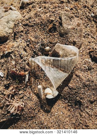 Plastic Pollution On The Beach. Single Use Plastic Cup And Cigarette Butt In Sand, Marine Trash On T