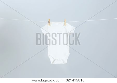 Cute Baby Onesie Hanging On Clothes Line Against Light Grey Background. Laundry Day
