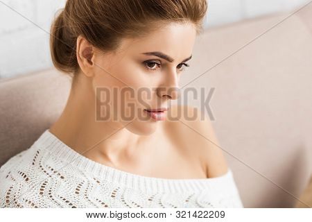Attractive Woman In White Sweater Looking Away In Apartment
