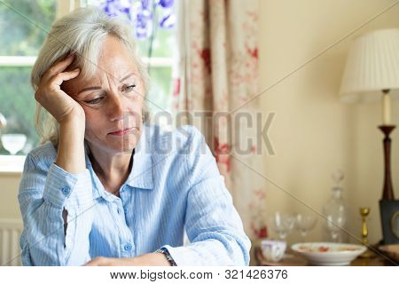Senior Woman Suffering With Depression With Head In Hands At Home