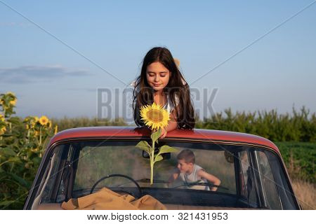 Calmy Cute Brunette Teen Girl Lies On The Roof Of The Red Retro Card Among The Field, Looking At The