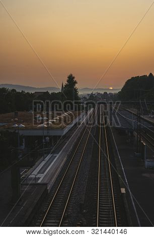 Train Station And Railroads At Sunrise. Railway Lines Leading Towards The Horizon. Strong Morning Su