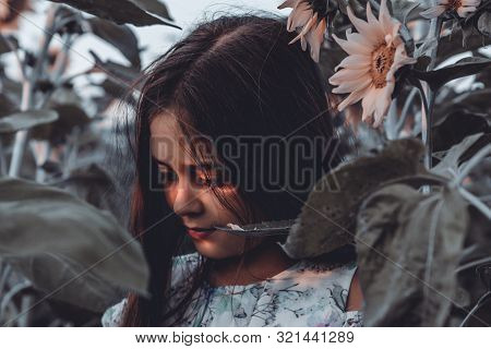 Close Up Portrait Of Beautiful Calmy Teen Girl With Brunetet Hair That Standing Among Sunflowers And