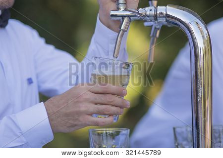 Cider Pouring Into A Glass From A Tap At A Traditional Oktoberfest Celebration