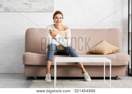 Attractive Woman In White Sweater Holding Pillow And Looking At Camera