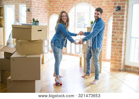 Young couple moving to a new home, having fun riding a skateboar
