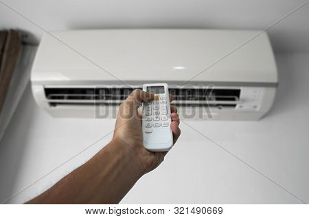 Mans Hand Using Remote Controler. Hand Holding Rc And Adjusting Temperature Of Air Conditioner Mount