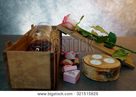 Red Wine Glass With Rose Flower On Concrete Table.