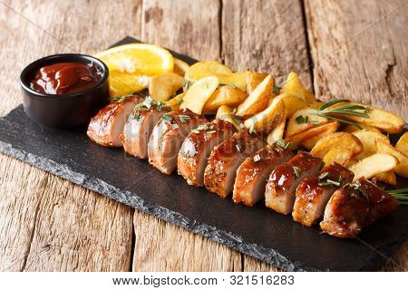 Traditional Baked Pork Tenderloin With Potato Wedges Close-up On A Slate Board. Horizontal