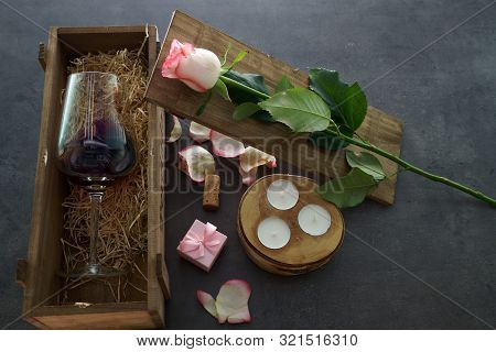 Red Wine Glass With Rose Flower On Concrete Table.