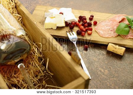 Red Wine Glass With Cheese And Salami In Wooden Box On Concrete Table