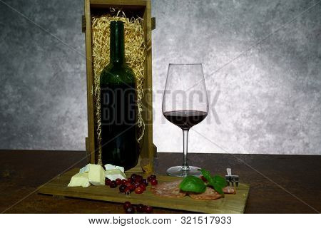 A Bottle Of Red Wine In A Wooden Box. Dark Background.