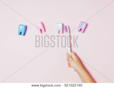 Childs Hands Holding Big Tooth And Toothbrush On Pink Backgroubd. Healty Care Teeth Concept. Top Vie