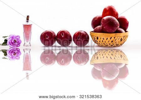 Raw Organic Red Ripe Plums In A Brown-colored Basket Isolated On White Along With Some Rose Water In