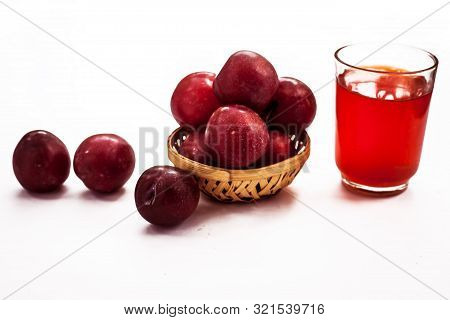 Raw Organic Red Ripe Plums In A Brown-colored Basket Along With Its Extracted Tincture Or Extracted