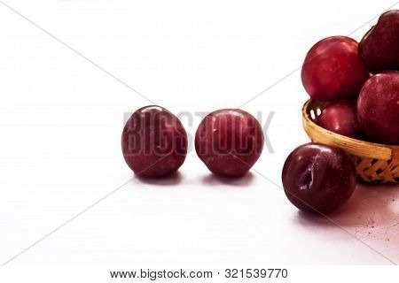 Raw Organic Red Ripe Plums In A Brown-colored Basket Isolated On White For Easy To Use For Any Purpo