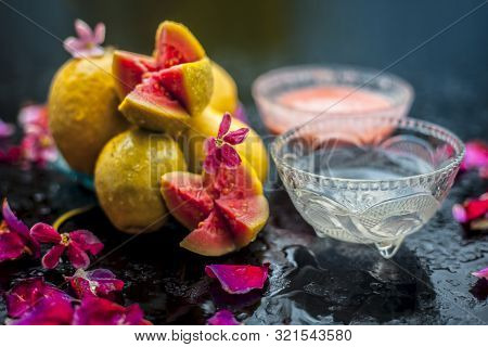 Guava Pulp And Water Well Mixed In A Glass Bowl On The Wooden Surface Along With Some Raw Cut Guava,