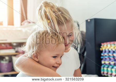 Cute Adorable Blond Caucaian Little Sister Hugging Her Toddler Brother.couple Of Cheerful Sibling Pl
