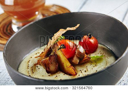 Restaurant Soup Food - Delicious Mushroom Soup with Garlic and Cherry Tomato. Gourmet Restaurant Soup Menu. Mushrooms Soup Garnished with Tea Broth and Garlic Mousse
