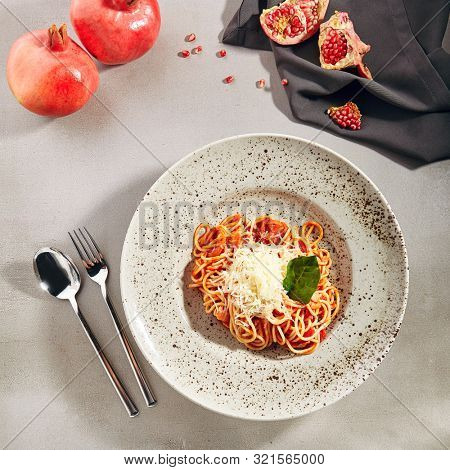 Classical Italian spaghetti with Amatriciana sauce, grated cheese and greens top view. Traditional homemade pasta with salsa alla matriciana based on guanciale, pecorino cheese, tomato, and onion